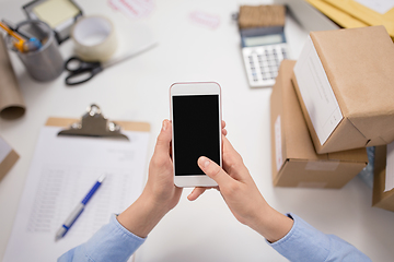 Image showing hands with smartphone and parcels at post office