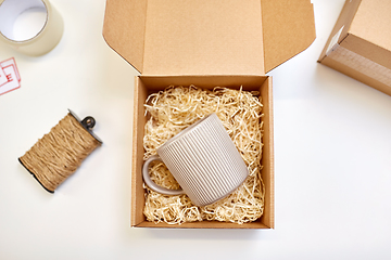 Image showing parcel with straw filler and mug at post office