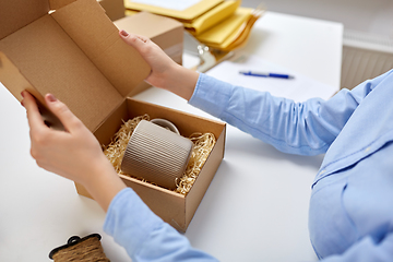 Image showing woman packing mug to parcel box at post office