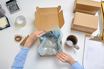 Image showing hands packing mug to parcel box at post office