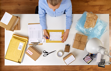 Image showing close up of woman filling postal form at office