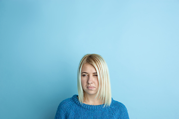 Image showing Portrait of young caucasian woman looks happy, dreamful on blue background