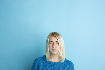 Image showing Portrait of young caucasian woman looks happy, dreamful on blue background