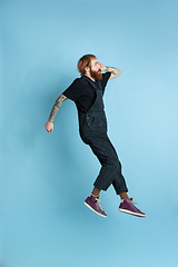 Image showing Portrait of young caucasian man looks happy, jumping on blue background