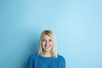 Image showing Portrait of young caucasian woman looks happy, dreamful on blue background