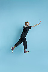 Image showing Portrait of young caucasian man looks happy, jumping on blue background