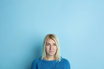 Image showing Portrait of young caucasian woman looks happy, dreamful on blue background