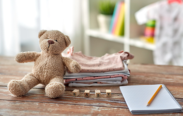 Image showing baby clothes, teddy bear, toy blocks and notebook