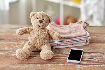 Image showing baby clothes, teddy bear toy and smartphone