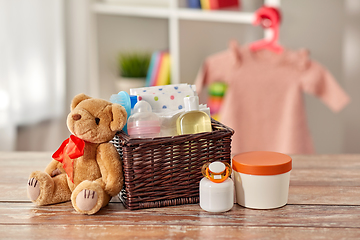 Image showing baby things in basket and teddy bear toy on table