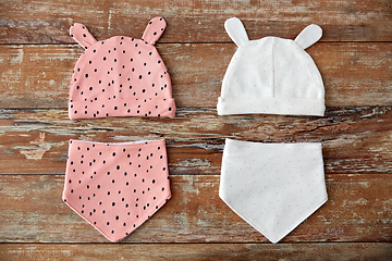 Image showing baby hats with ears and bibs on wooden table