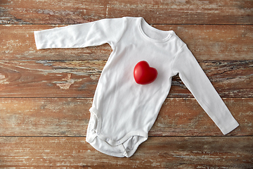 Image showing baby bodysuit with red heart toy on wooden table