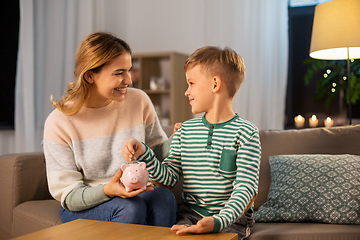 Image showing mother and little son with piggy bank at home