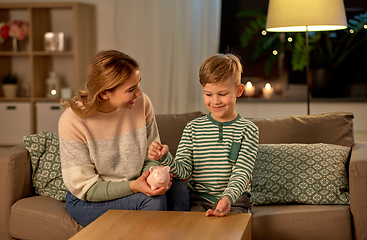 Image showing mother and little son with piggy bank at home