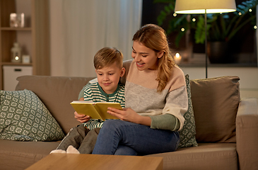 Image showing happy mother and son reading book sofa at home