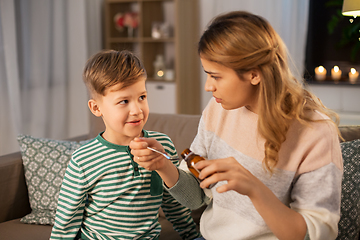 Image showing mother giving medication or cough syrup to ill son