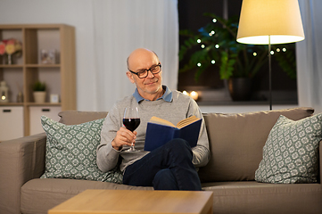 Image showing happy senior man drinking wine and reading book