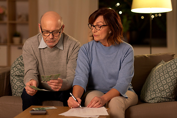 Image showing senior couple with bills counting money at home