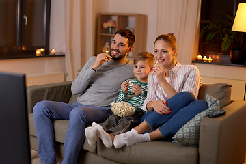 Image showing happy family with popcorn watching tv at home