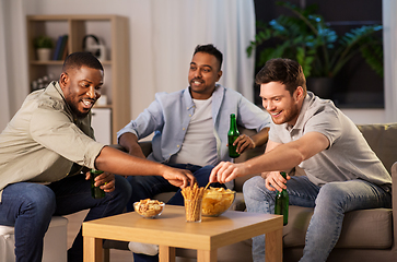 Image showing male friends drinking beer with crisps at home