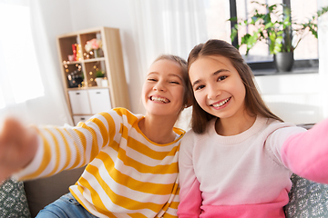 Image showing happy teenage girls taking selfie at home