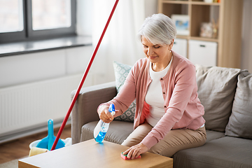 Image showing senior woman with detergent cleaning table at home