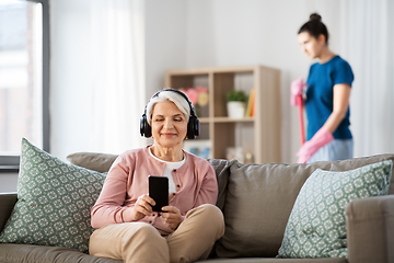 Image showing old woman in headphones with smartphone at home