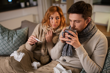 Image showing sick couple with thermometer and tea at home