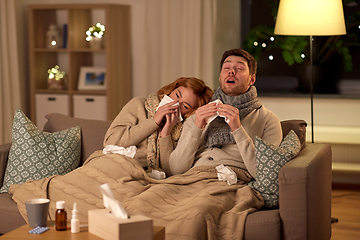 Image showing sick young couple with tissue blowing nose at home