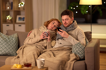 Image showing sick young couple with smartphone at home