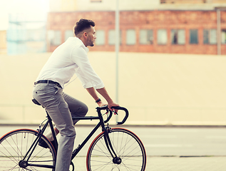 Image showing man with headphones riding bicycle on city street