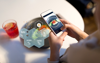 Image showing hands with phone and food nutritional value chart