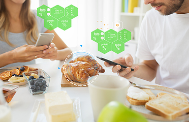 Image showing couple with smartphones having breakfast at home