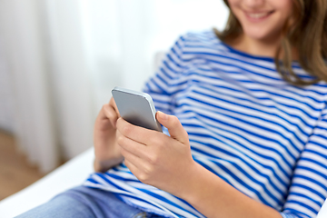 Image showing smiling teenage girl using smartphone at home