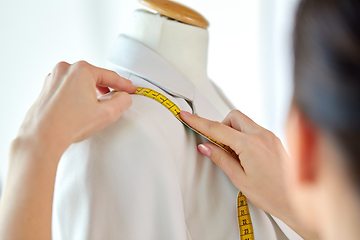 Image showing fashion designer measures jacket with tape measure