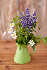 Image showing bunch of herbs and flowers in green jug on table