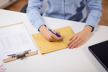 Image showing woman writing on parcel envelope at post office