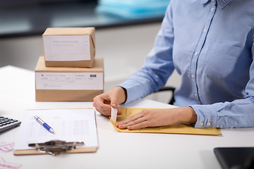 Image showing woman removing sticker from envelope with parcel