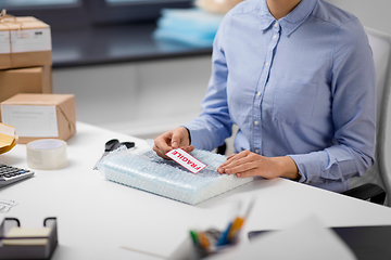 Image showing woman sticking fragile mark to wrap at post office