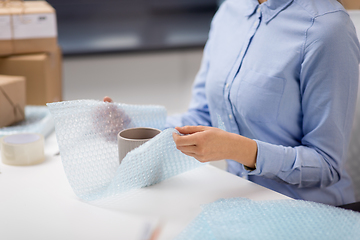 Image showing woman packing mug to parcel box at post office