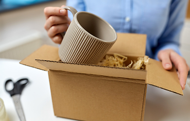 Image showing woman packing mug to parcel box at post office