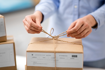 Image showing woman packing parcel and tying rope at post office