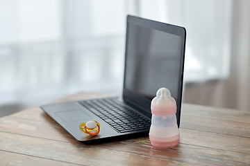 Image showing baby milk formula, laptop and soother on table