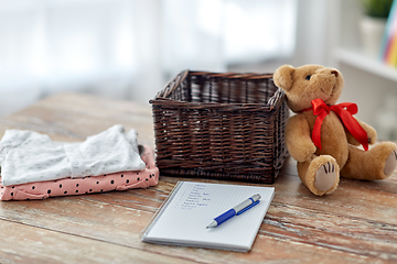 Image showing baby clothes, teddy bear, toy blocks and notebook