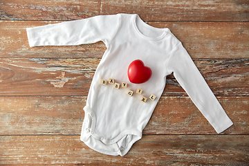 Image showing baby bodysuit with red heart on wooden table