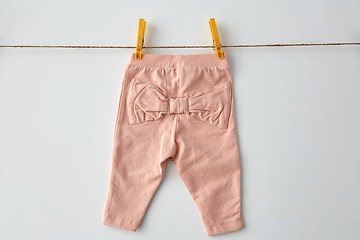 Image showing pink pants for baby girl on clothesline with pins