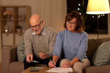 Image showing senior couple with bills counting money at home