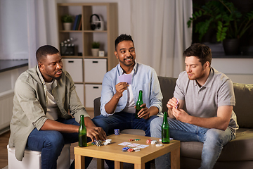 Image showing happy male friends playing cards at home at night