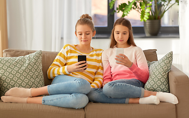 Image showing girls with smartphones sitting on sofa at home