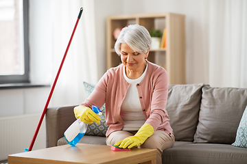 Image showing senior woman with detergent cleaning table at home